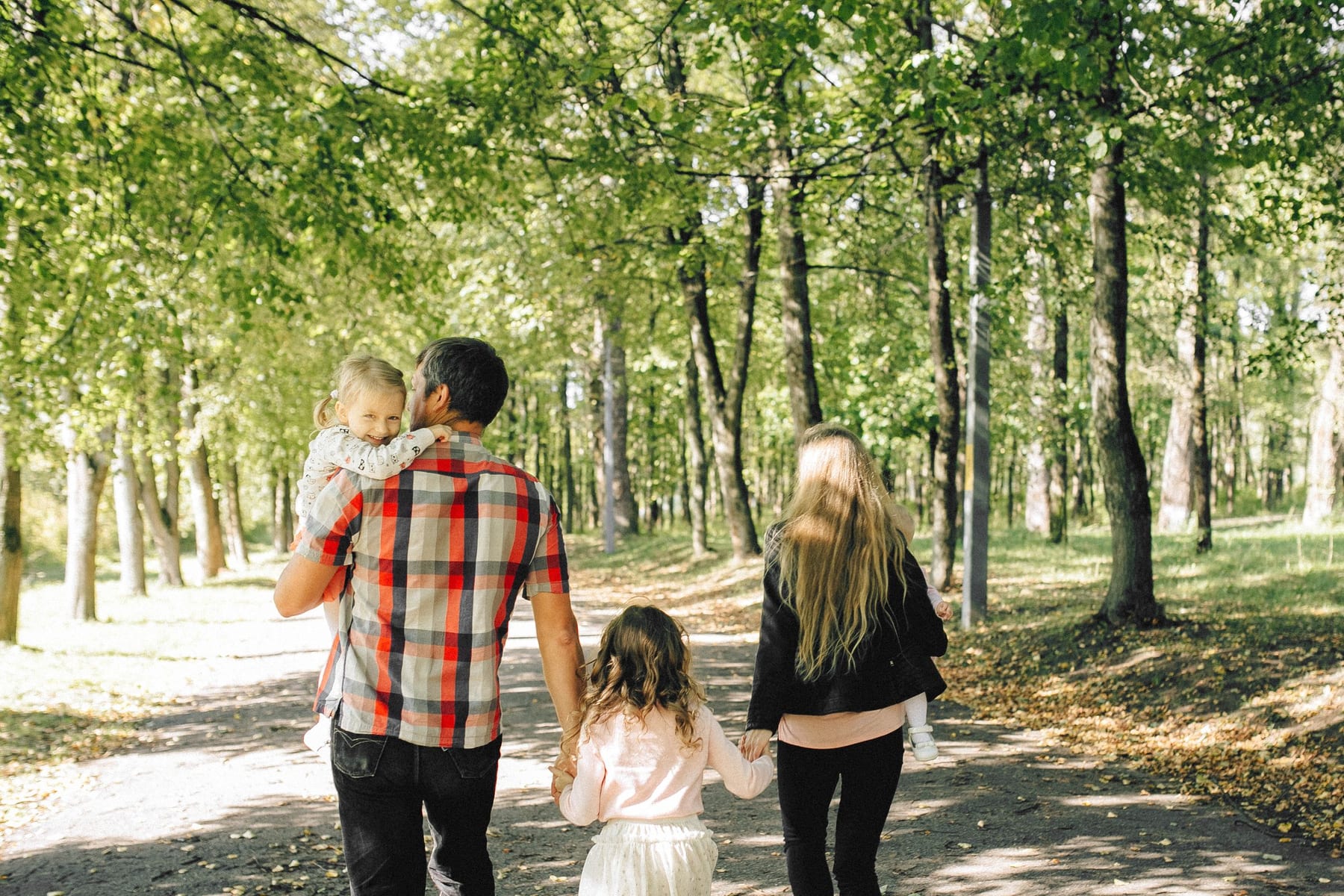 A family walking together through a sunlit park.